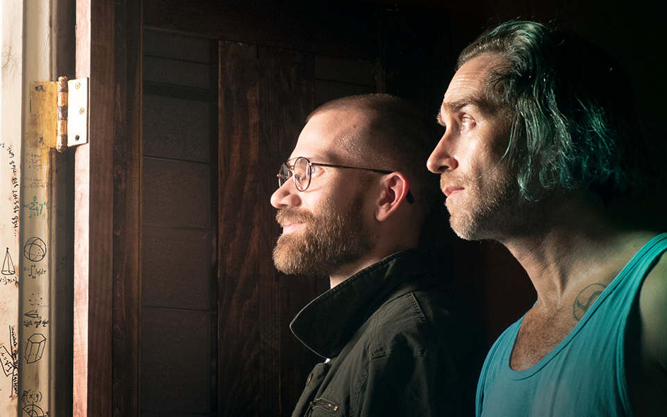 Two people looking out a doorway in dim light.