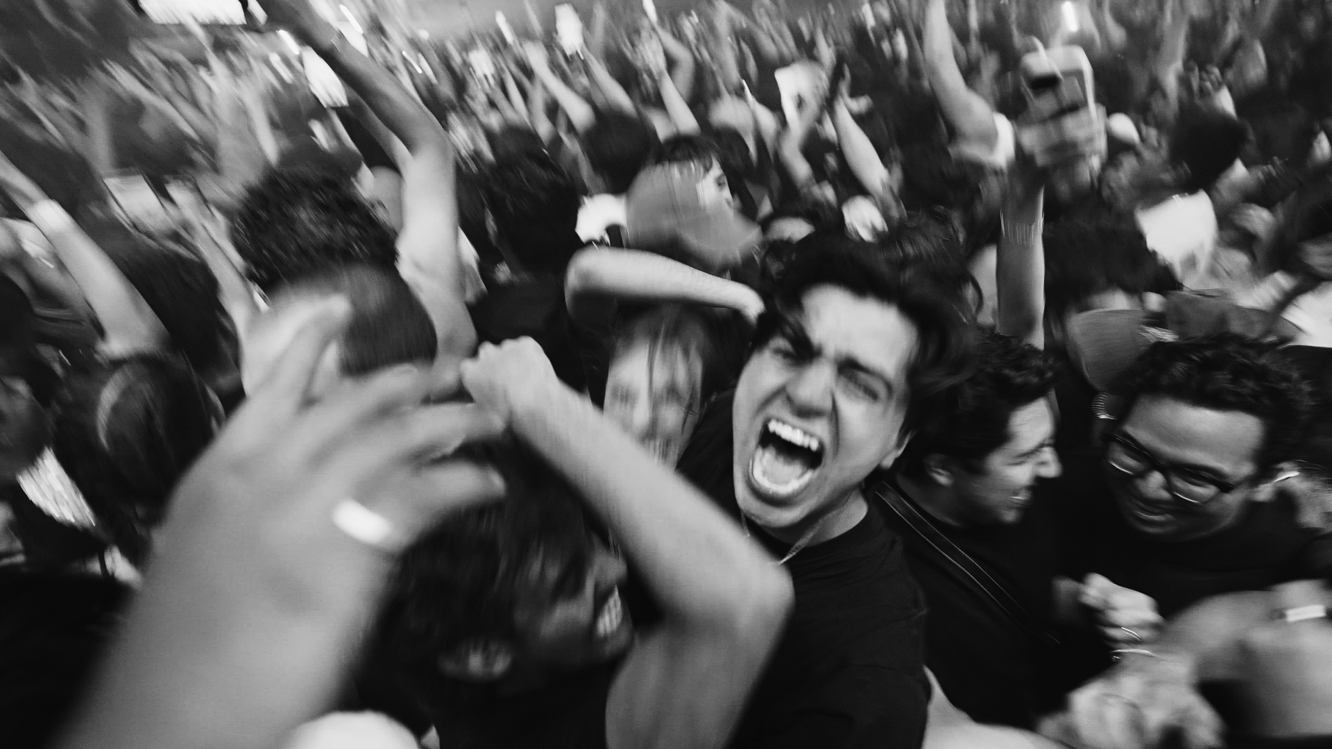Black-and-white photo of a crowded dance floor with people cheering and embracing