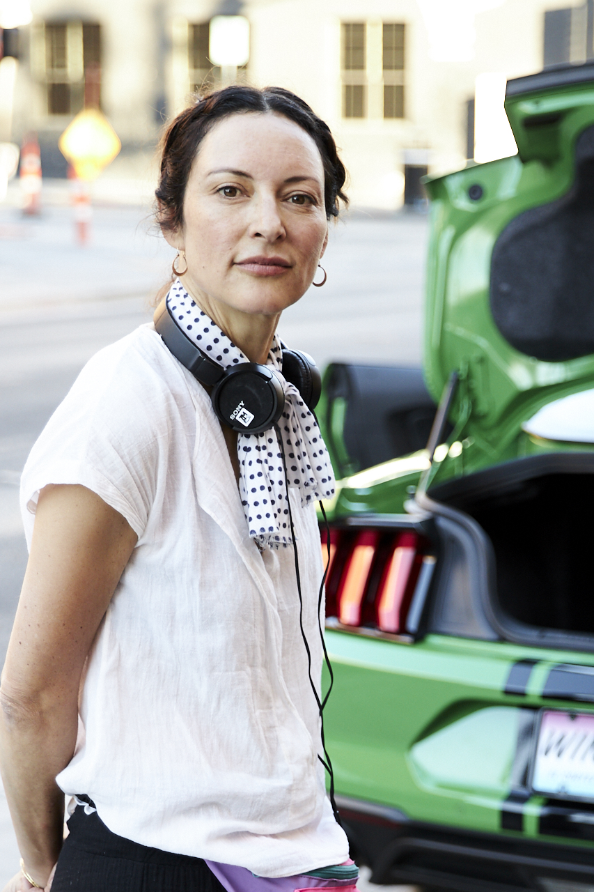  - Woman beside an open green car trunk