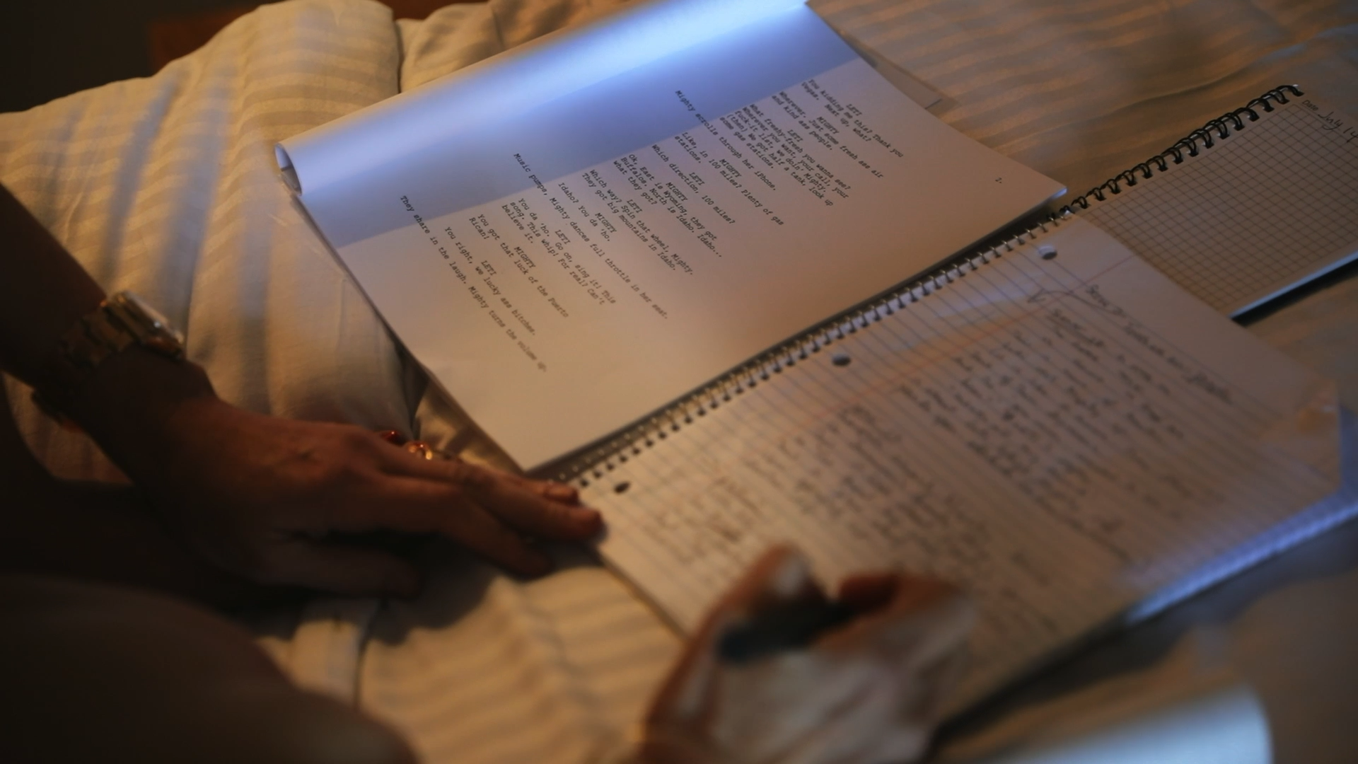 Hands reading a script and notebook