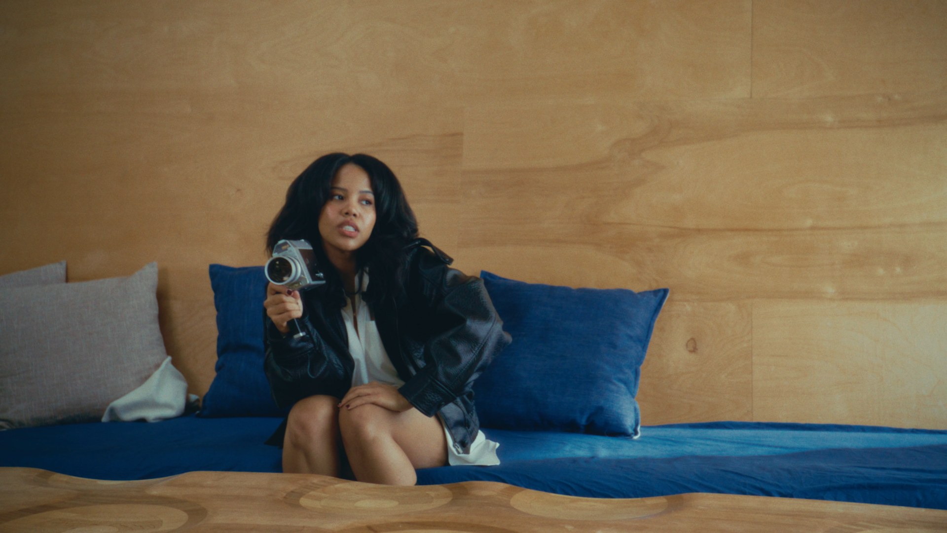 Baby Rose sits on blue couch holding a video camera