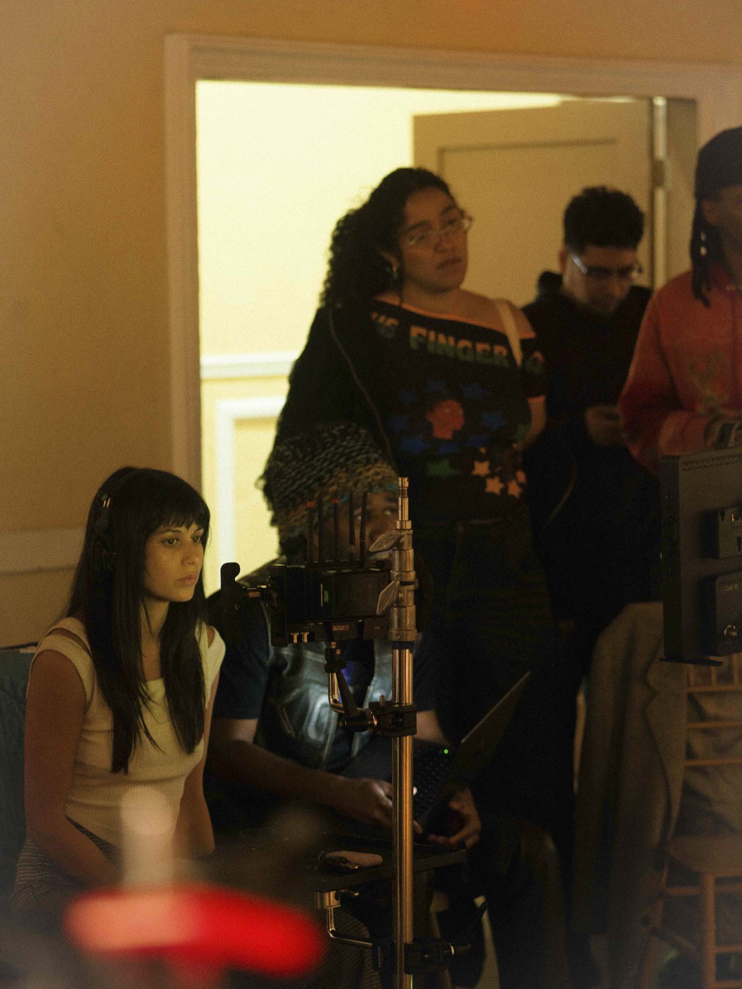 Film crew gathers around camera and monitor during production