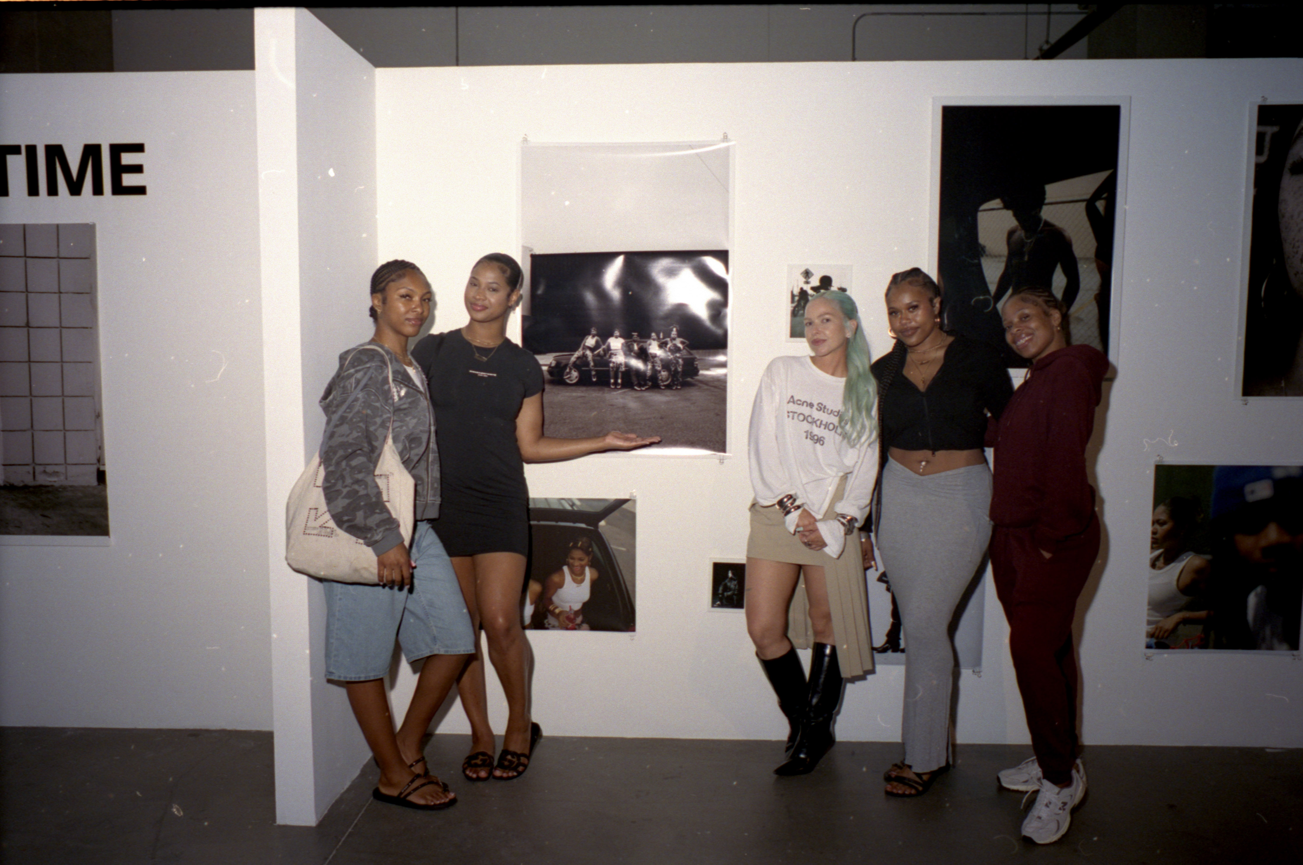 Five people pose together in front of photographs displayed on gallery walls