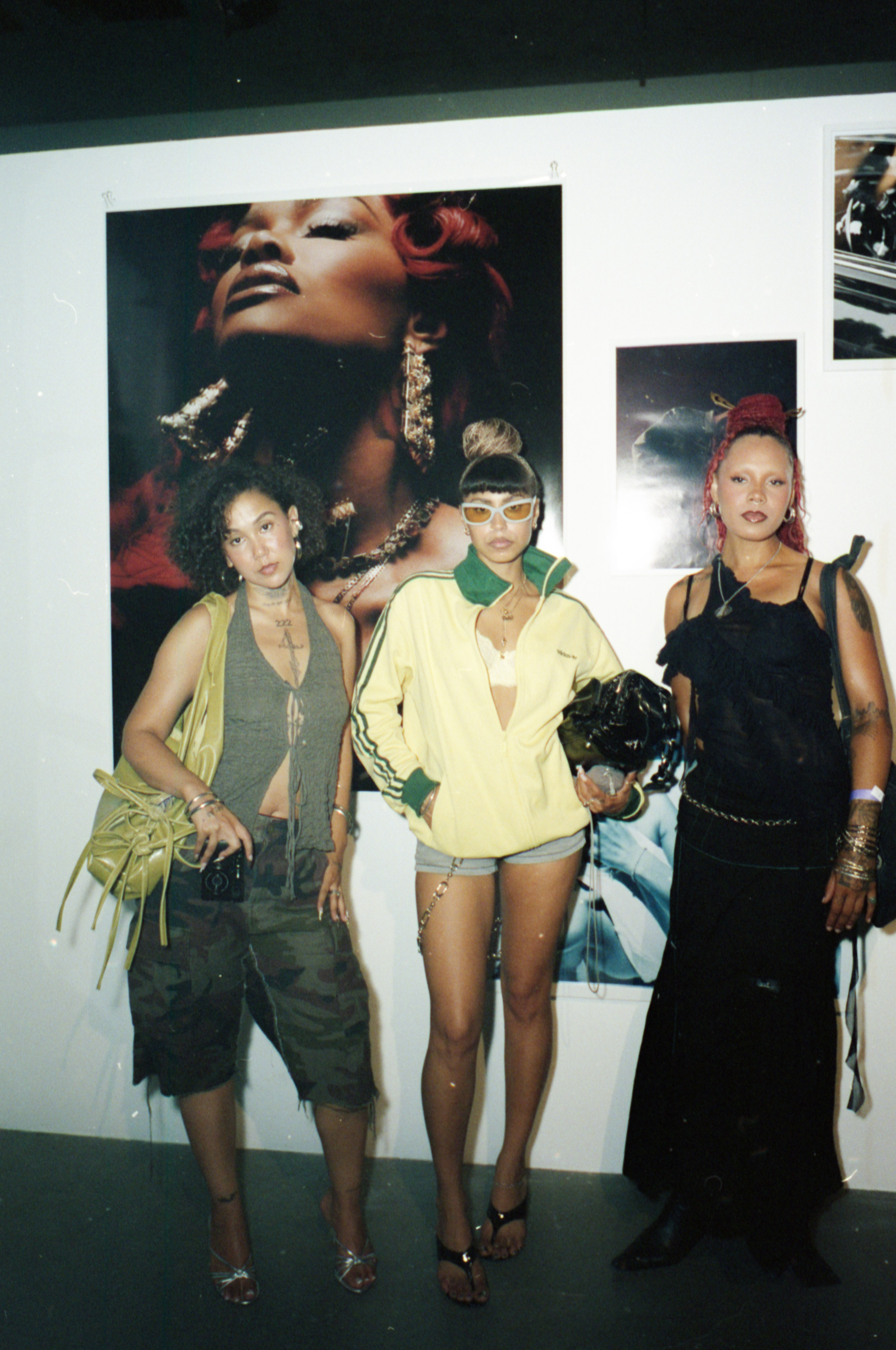 Three people pose together in front of large portraits displayed at photo exhibition