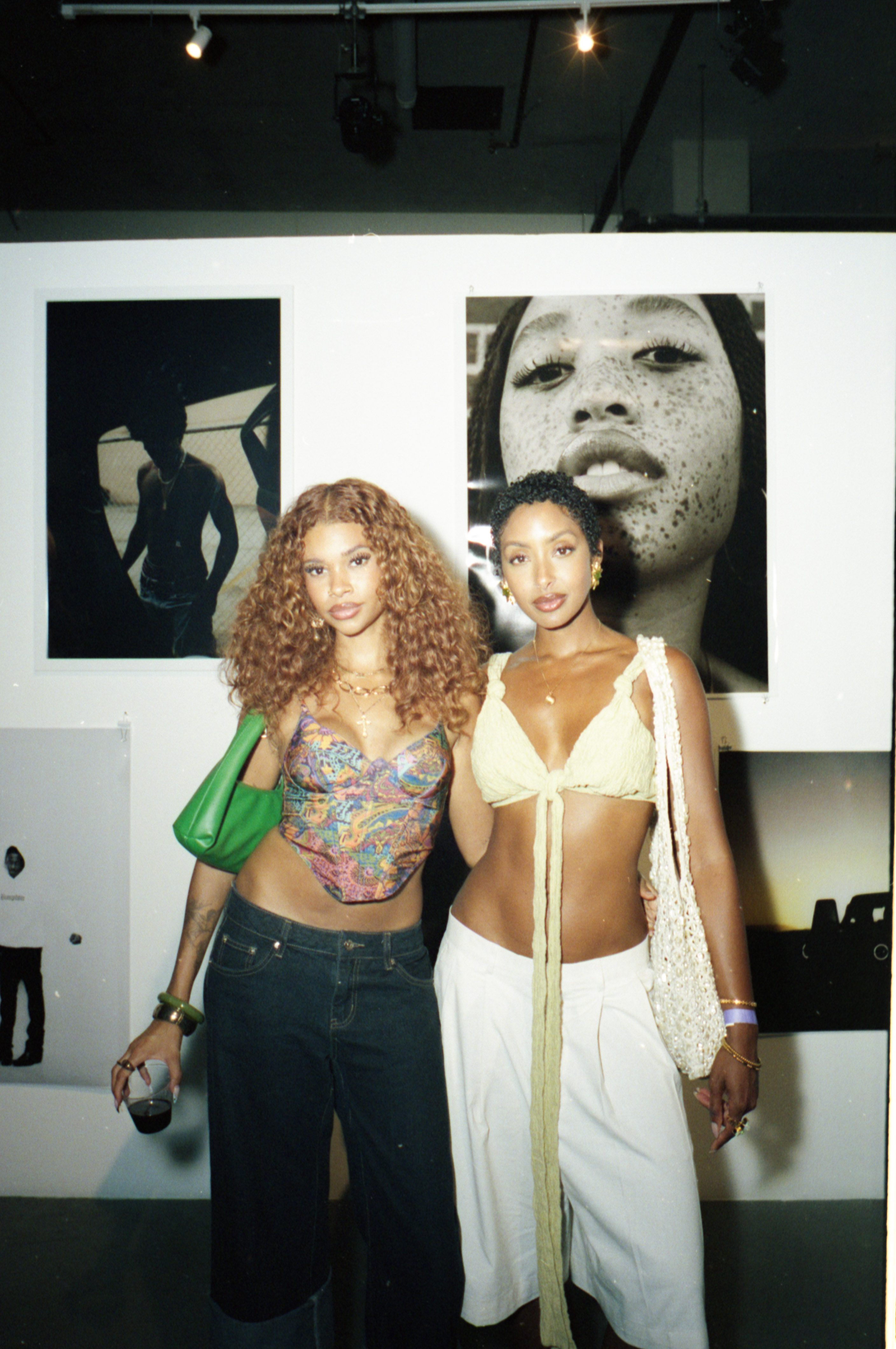 Two people pose together in front of large portraits displayed at photo exhibition