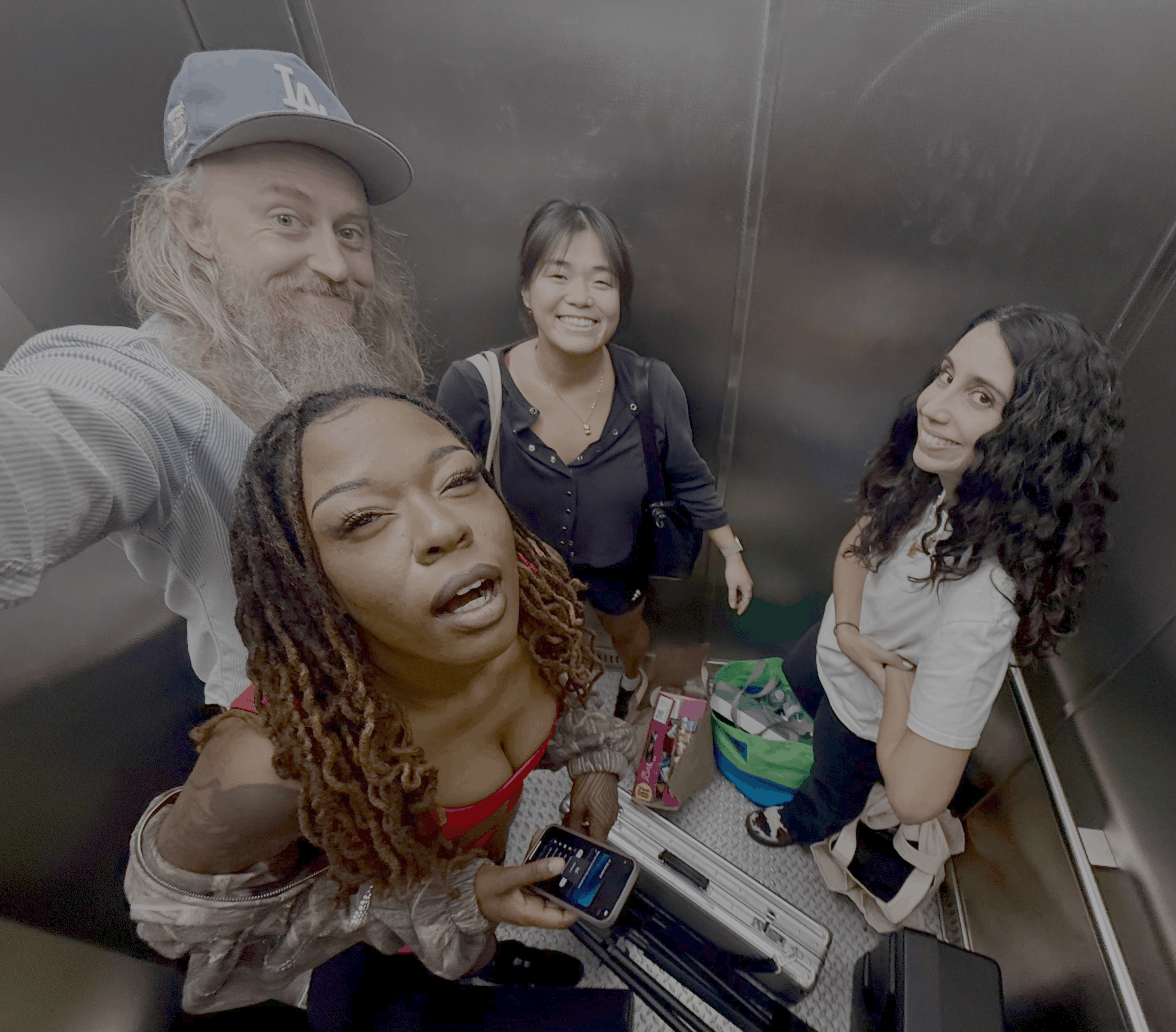 Four people pose together for a selfie inside an elevator