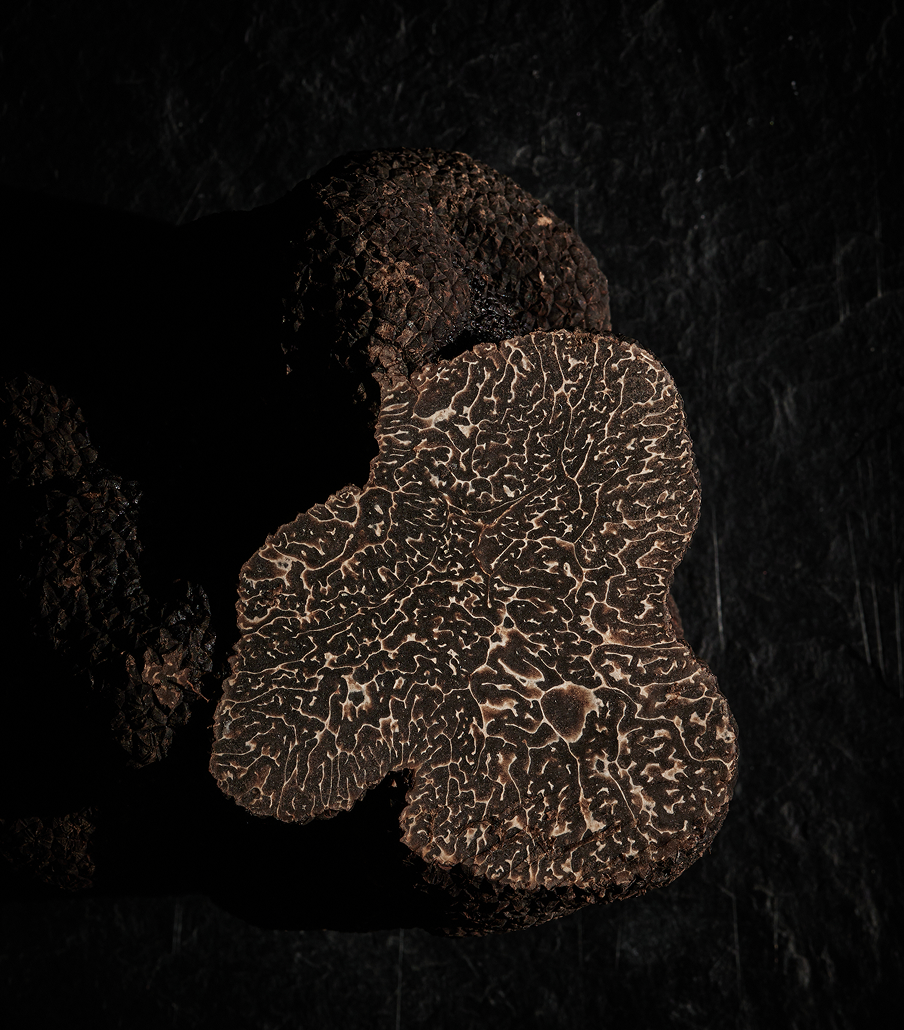 Close-up of a sliced black truffle showing its intricate marbled interior pattern.