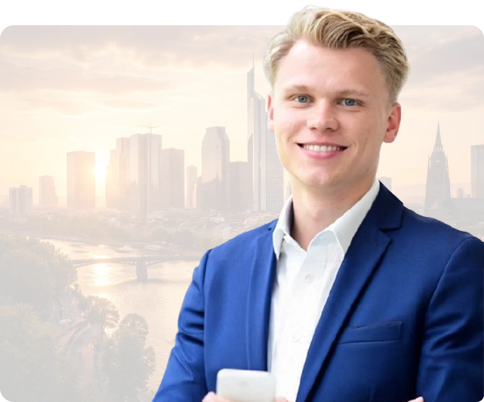 Junger Mann im blauen Anzug lächelt vor einer Stadtkulisse bei Sonnenuntergang.
