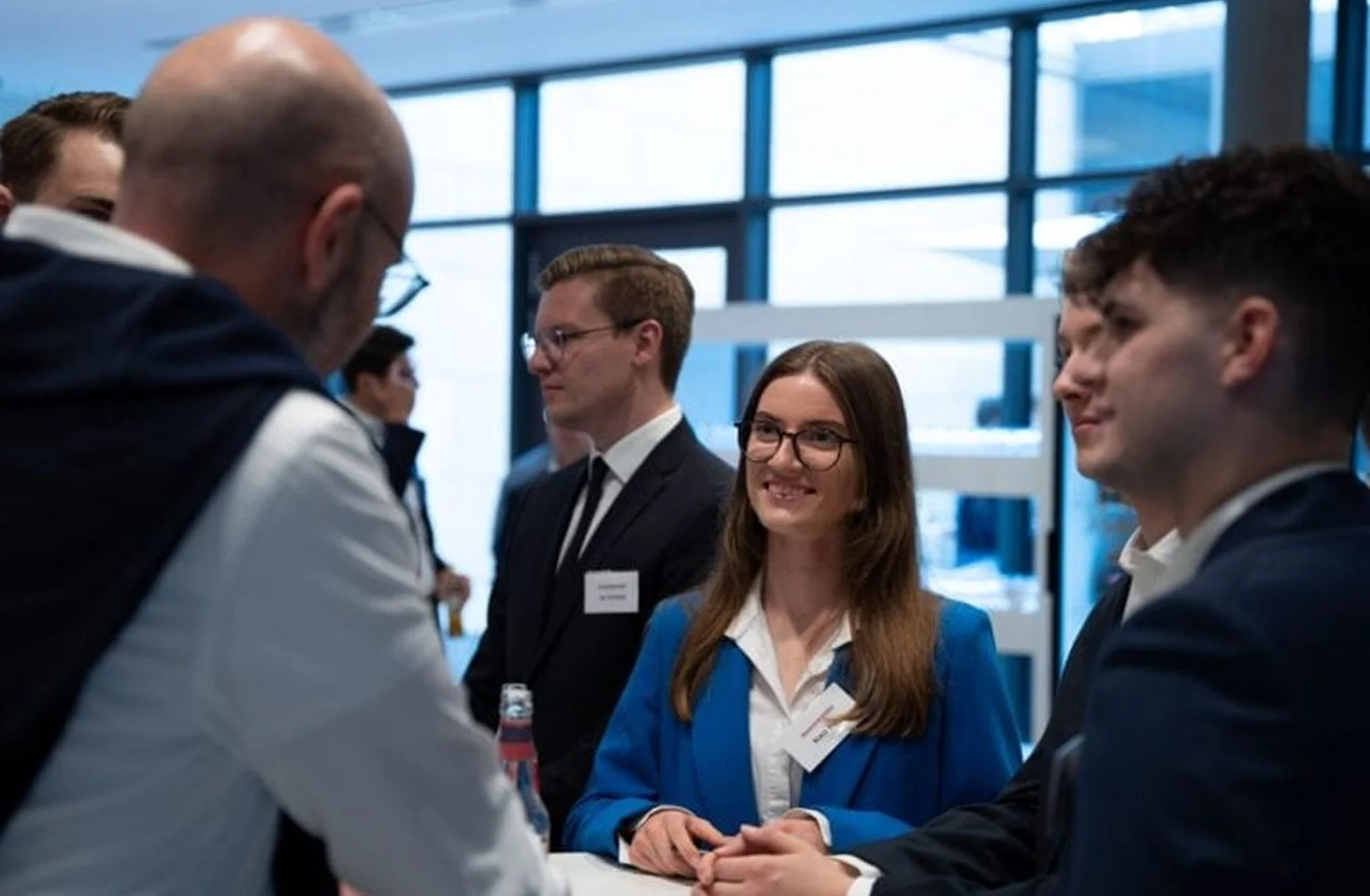 Menschen in Businesskleidung unterhalten sich bei einer Netzwerkveranstaltung mit Aktienflaschen.
