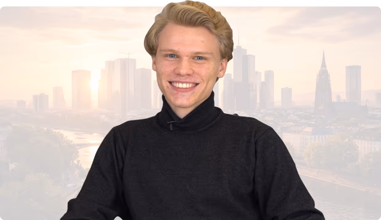Junger Mann mit hellem Haar und schwarzem Rollkragenpullover lächelt vor verschwommener Stadtkulisse.