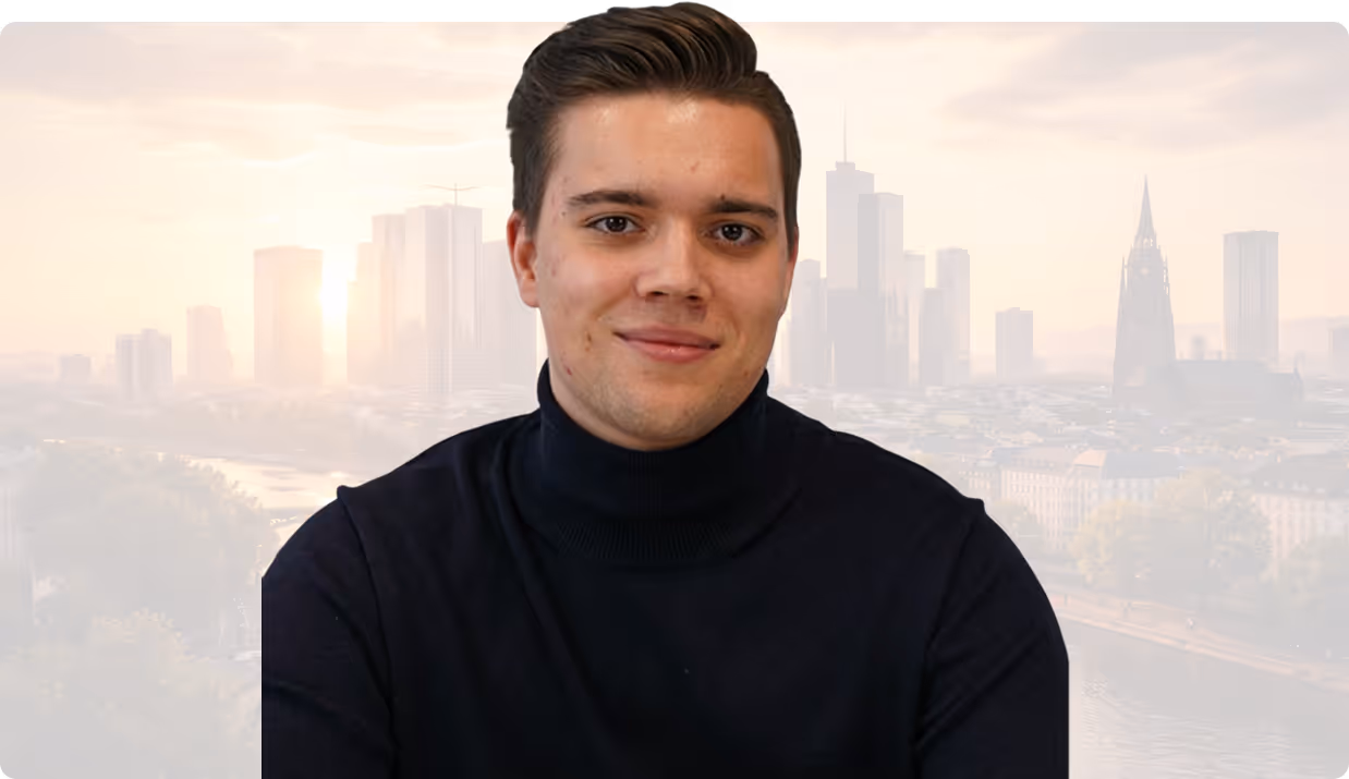Junger Mann mit dunklem Rollkragenpullover und Stadtblick im Hintergrund bei Sonnenuntergang.