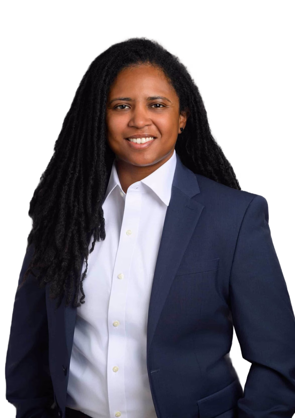 Smiling person with long black dreadlocks wearing a white shirt and dark blue blazer against a black background.