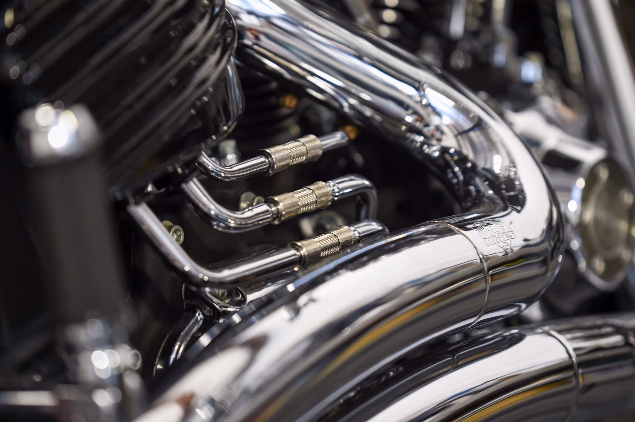 Close-up of shiny chrome motorcycle exhaust pipes with clamps.
