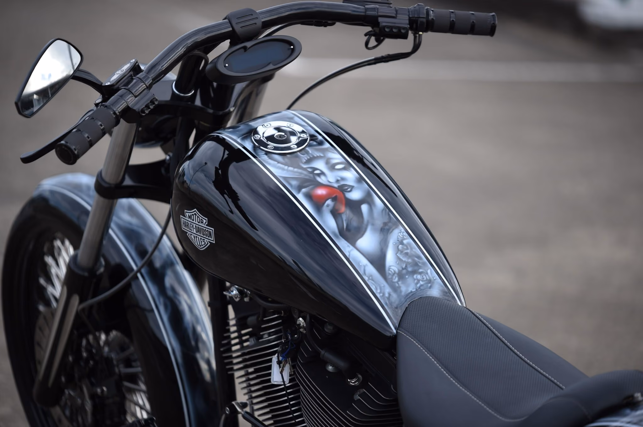 Close-up of black Harley-Davidson motorcycle gas tank with artwork of woman holding a red apple.