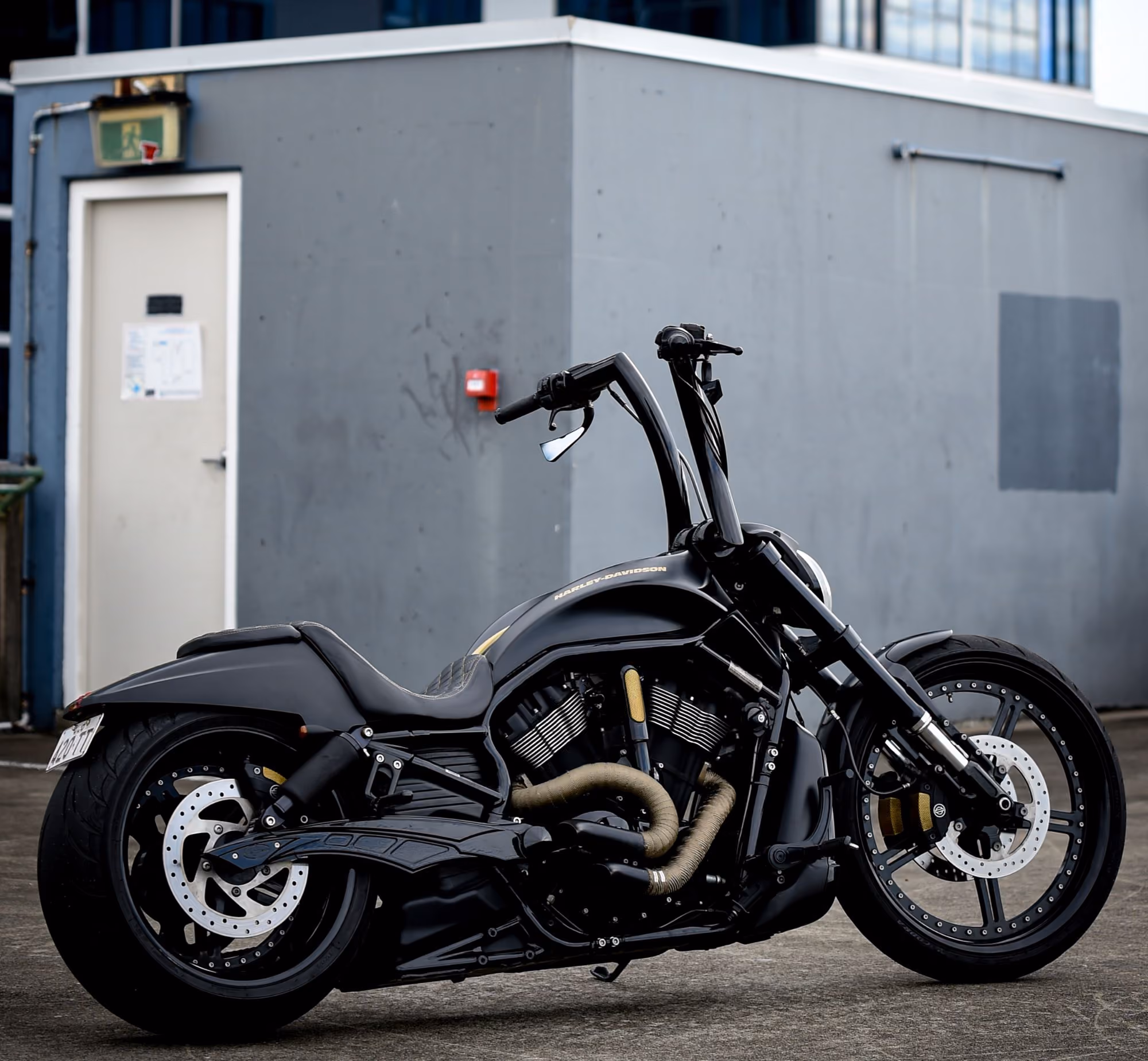 Black Harley-Davidson motorcycle parked on concrete with tall black handlebars and visible engine details.