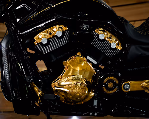 Close-up of a black motorcycle engine with multiple shiny gold parts and details.
