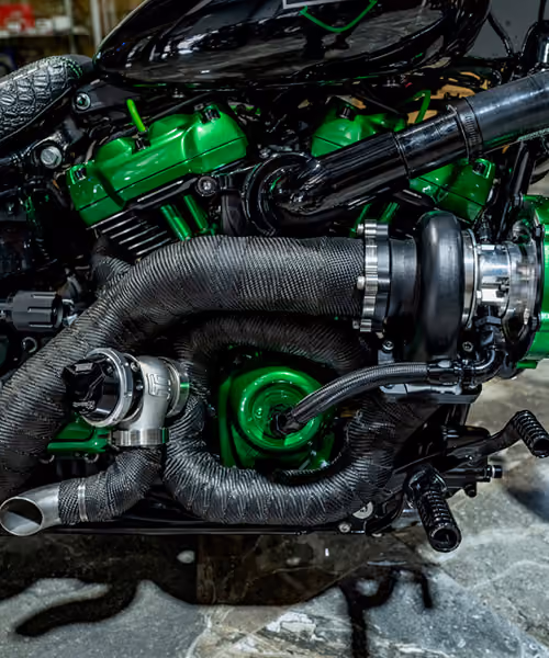 Close-up of a motorcycle engine with black exhaust wraps and bright green parts.