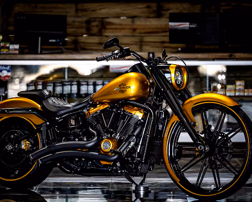 Golden and black Harley-Davidson motorcycle parked indoors with wooden background.