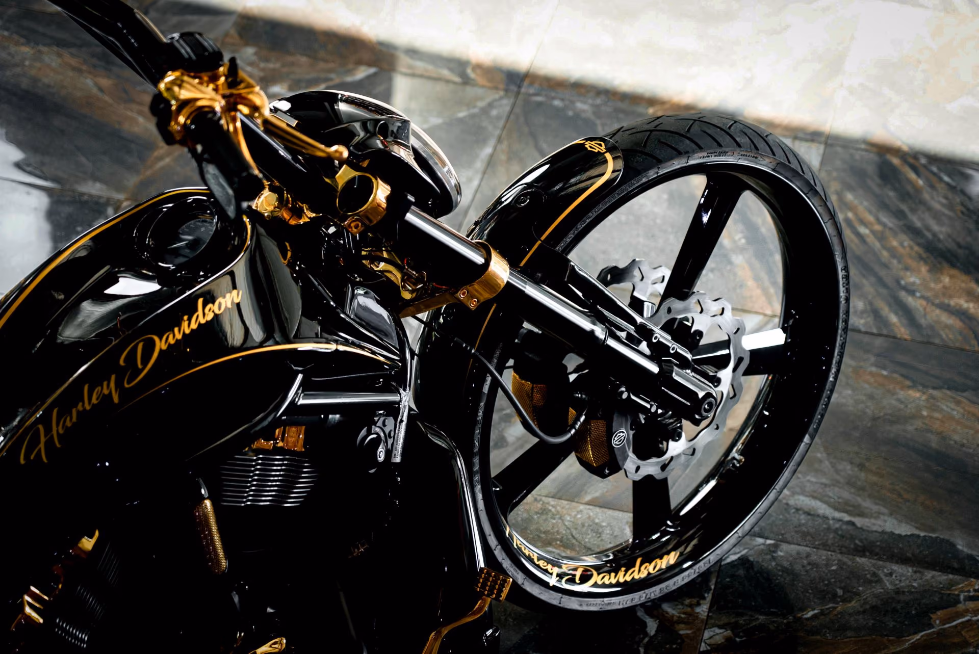 Close-up of a black Harley Davidson motorcycle front wheel and tank with gold accents.