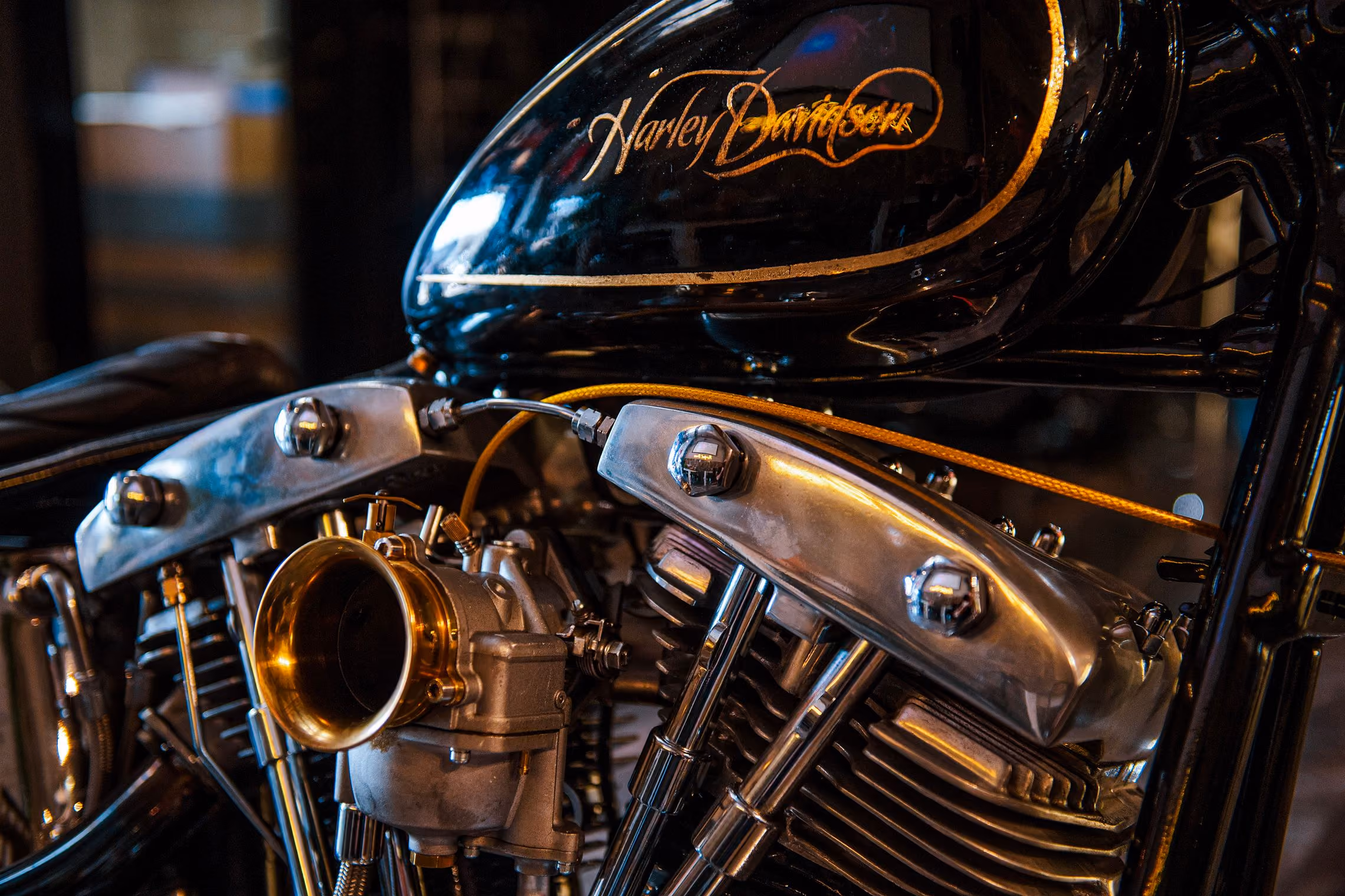 Close-up of a Harley-Davidson motorcycle engine with a black fuel tank featuring gold logo.