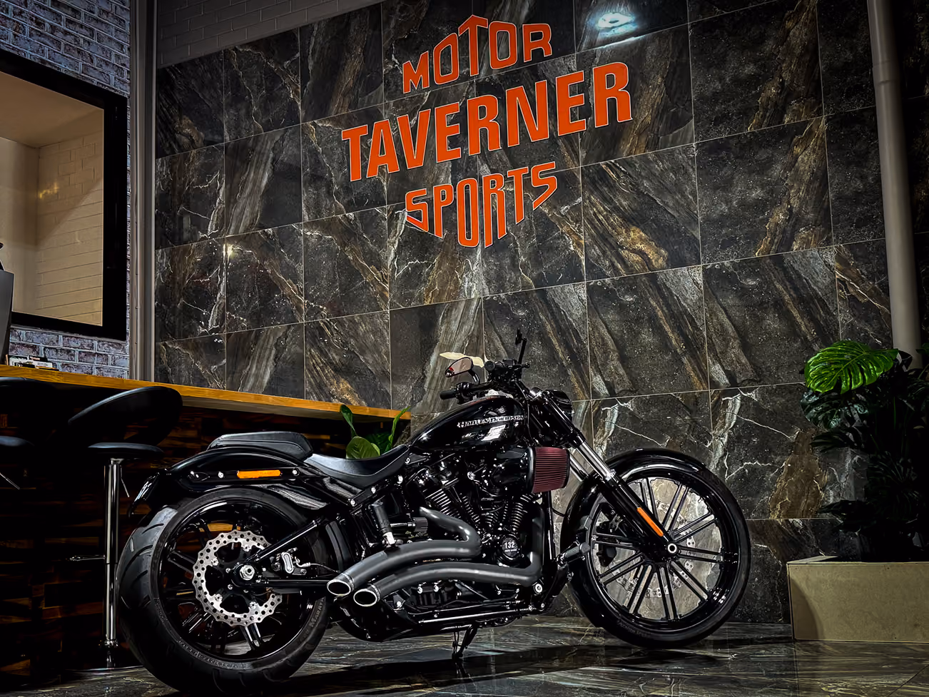 Black Harley-Davidson motorcycle parked indoors against a dark marbled wall with red text.