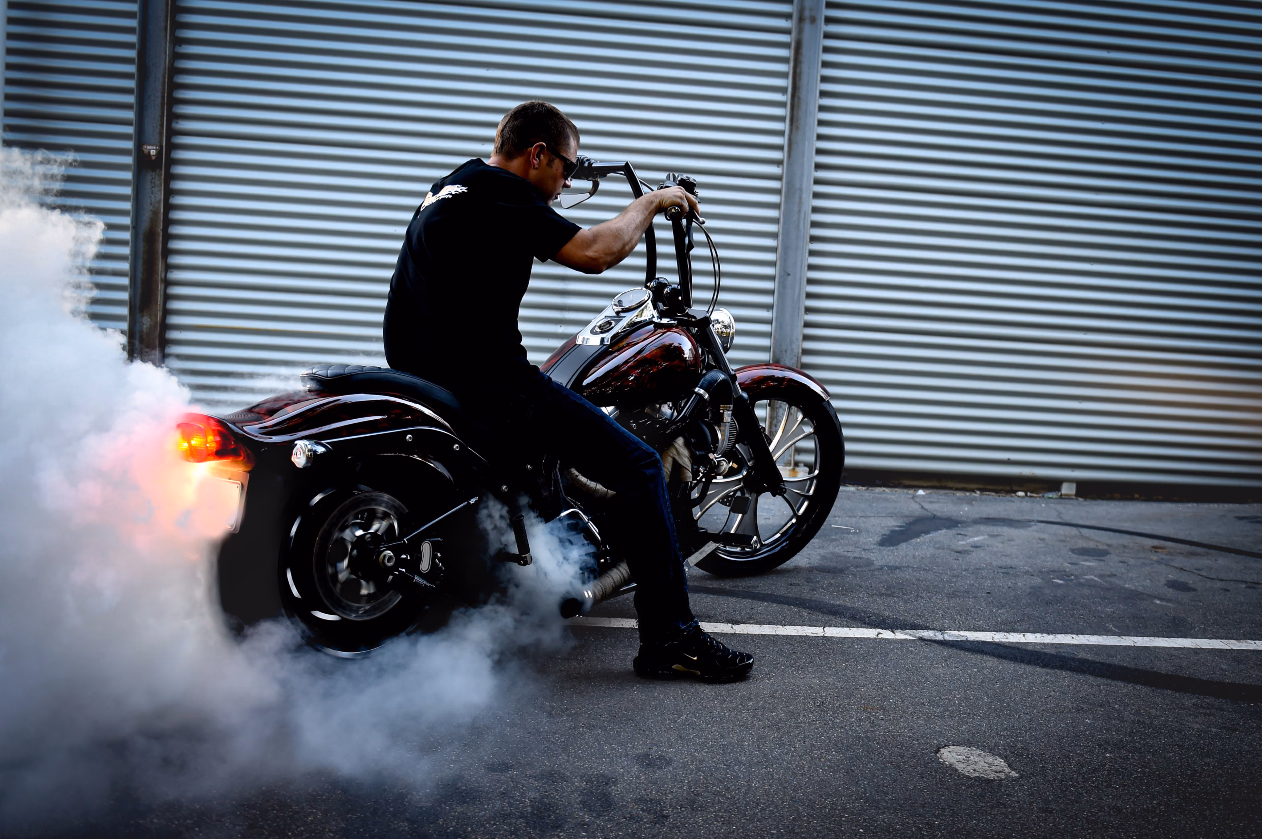 Man performing a burnout on a red motorcycle, causing smoke from the rear tire.