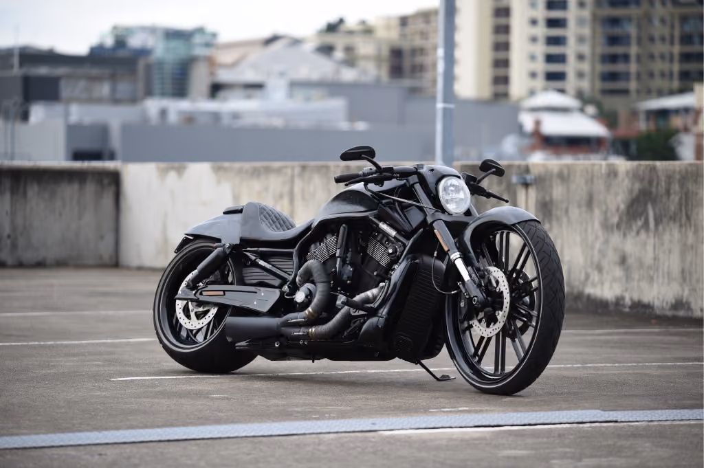 Sleek black custom motorcycle parked on rooftop with city buildings blurred in background.