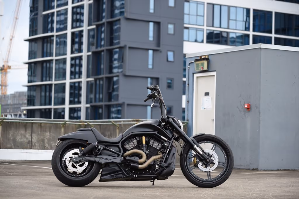 Black custom motorcycle parked on urban rooftop with modern buildings in the background.