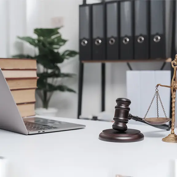 A laptop, gavel, and scale of justice arranged on a desk, symbolizing legal work and technology integration.