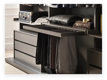 Rangements modernes avec pantalons suspendus sous une tablette coulissante et accessoires sur les étagères.