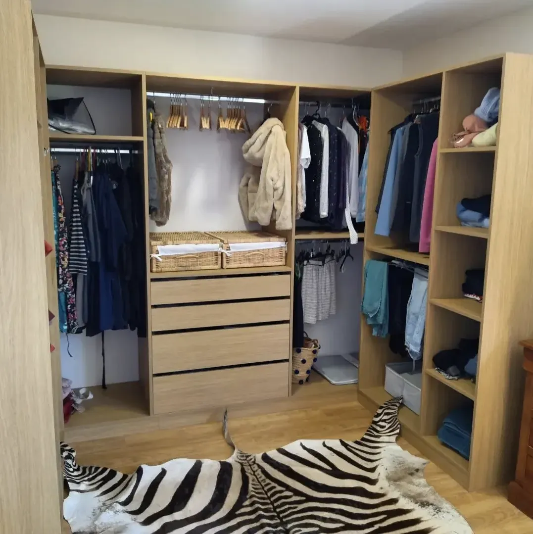 Dressing avec des vêtements suspendus, tiroirs en bois et un tapis imitation peau de zèbre au sol.