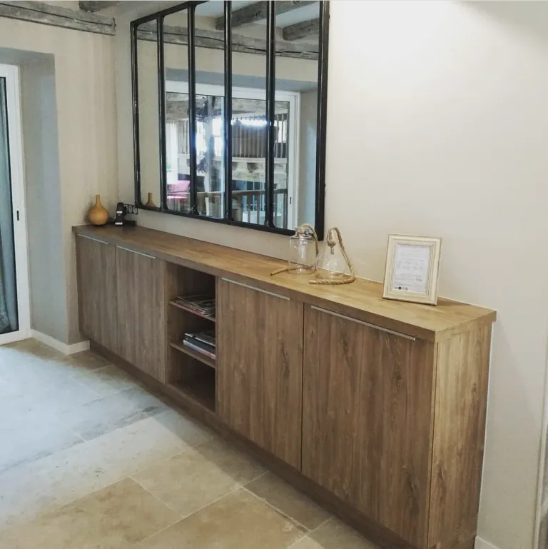 Meuble bas en bois avec des portes et des étagères ouvertes, décoré de vases en verre et d'un cadre, miroir à plusieurs panneaux au-dessus.