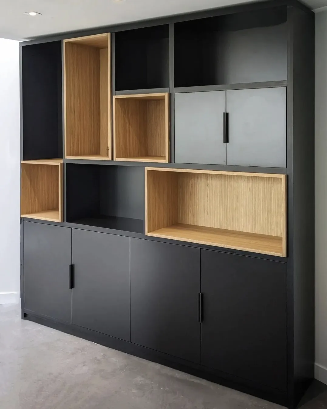 Un meuble de rangement moderne en bois et noir avec plusieurs étagères ouvertes et des portes fermées.