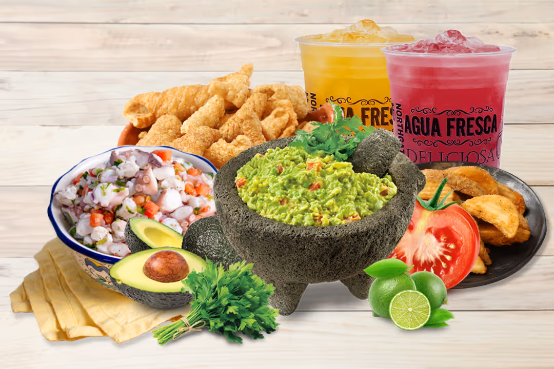 Hand with bright pink nails dipping a tortilla chip into a bowl of guacamole with visible tomato pieces.