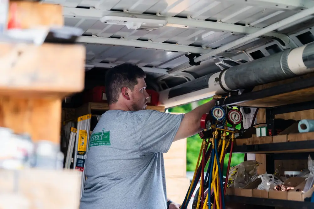Korrect technician reaching for refrigerant manifold gauges in a stocked service van