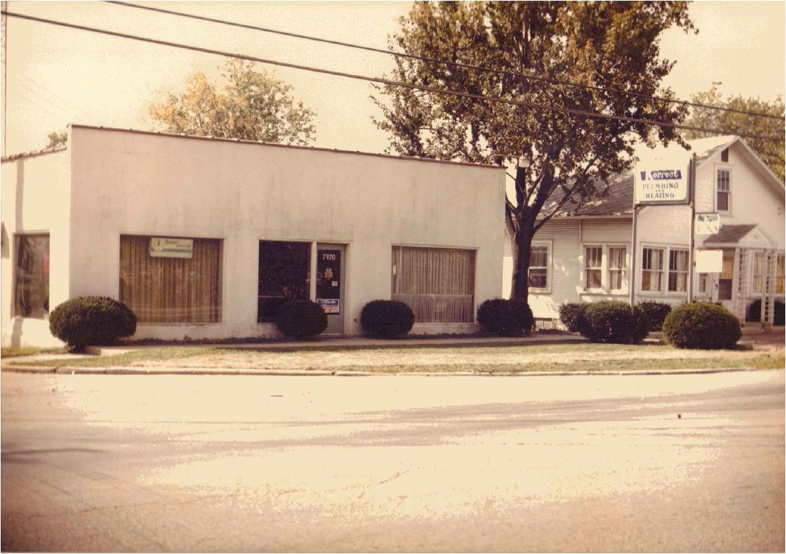 Korrect's first office, a small white storefront with a plumbing and heating street sign