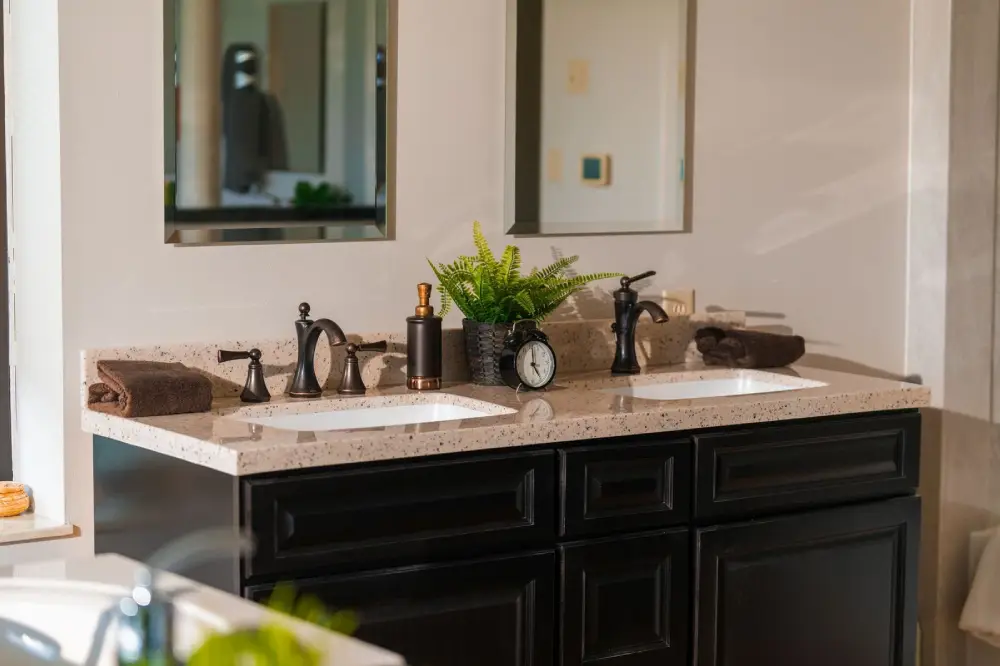 Double-sink bathroom vanity with bronze faucets and speckled stone countertop