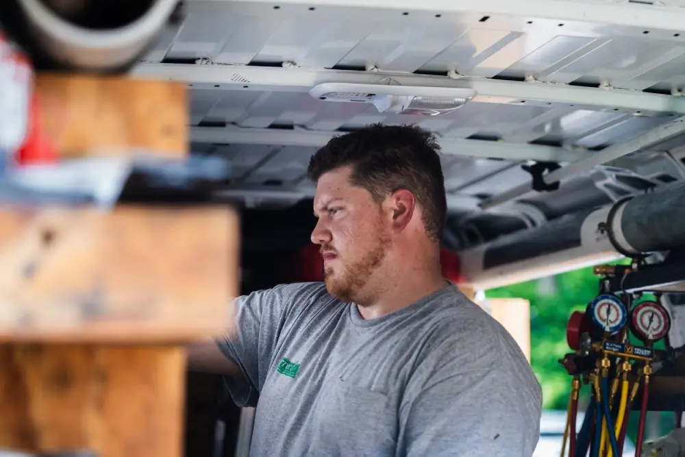 Korrect technician in a service van beside red and blue refrigerant manifold gauges