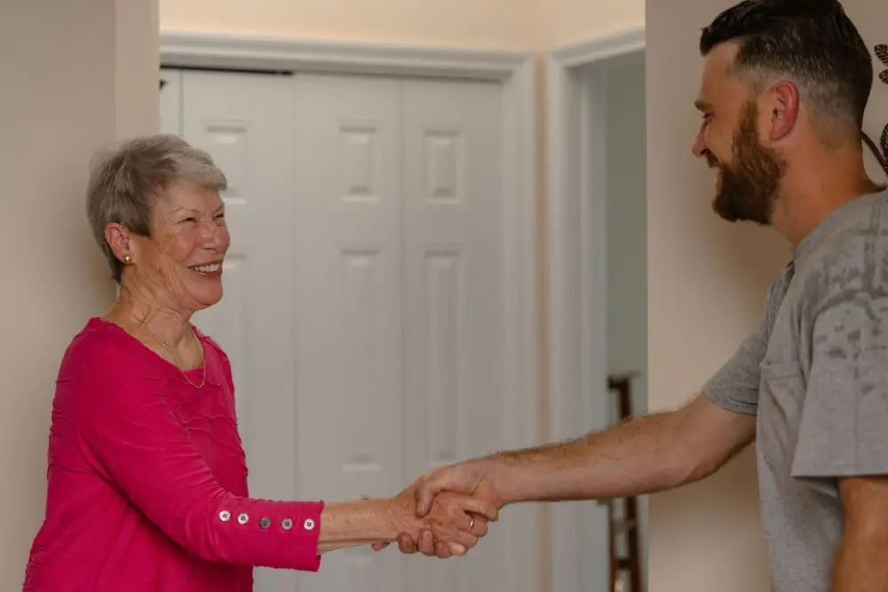 Korrect technician shaking hands with a smiling older homeowner in her entryway