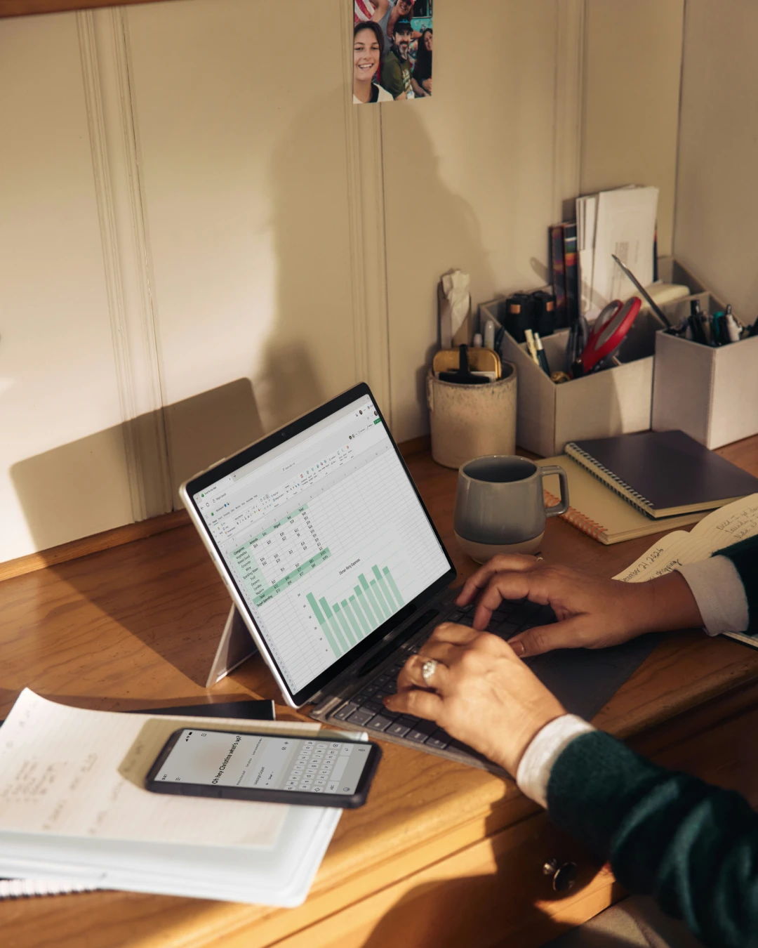 Bookkeeper working at a desk, reviewing financial data and spreadsheets on a laptop while using a calculator and organizing business documents.