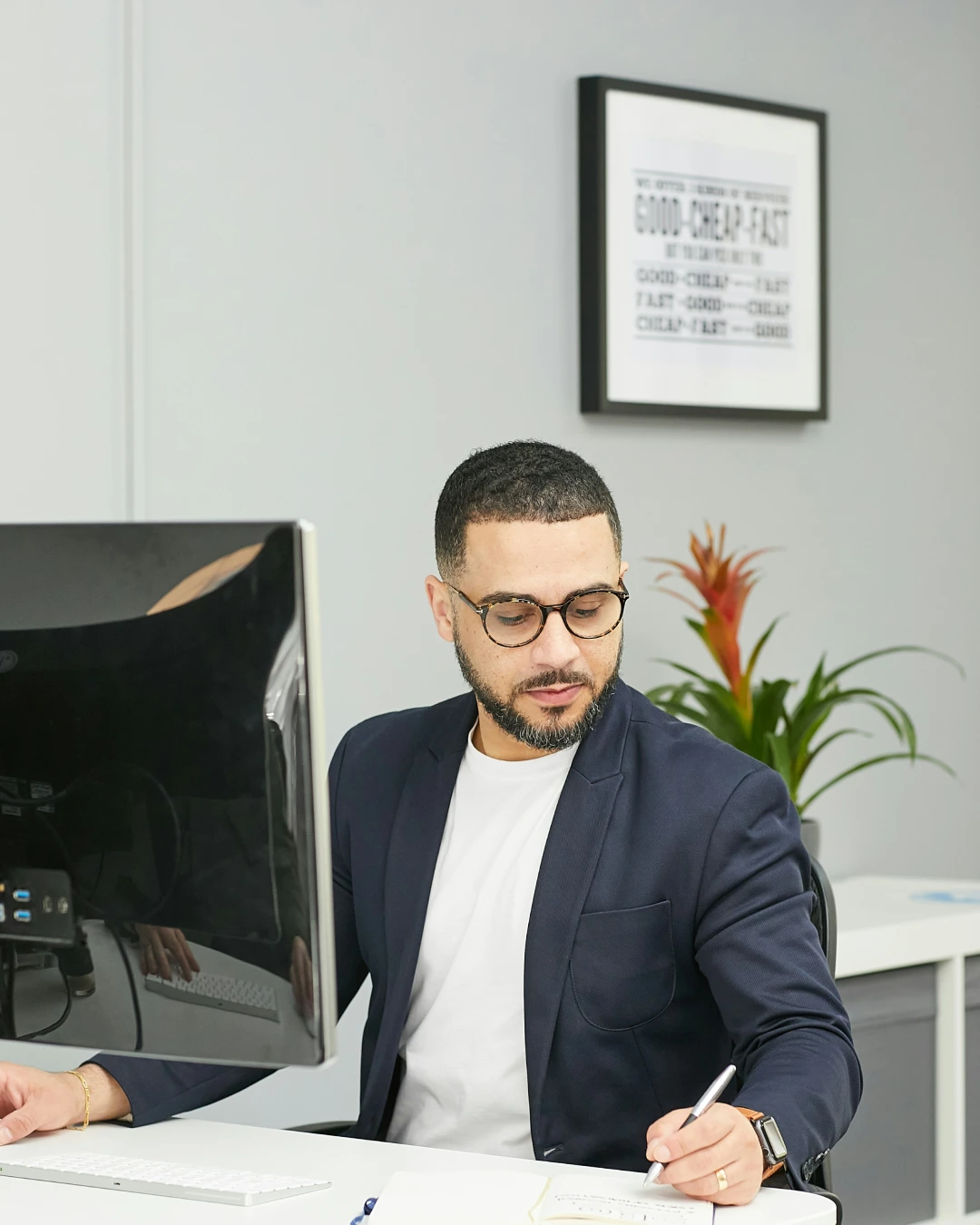 Operations Manager working at a desk, reviewing notes and managing business operations on a computer.