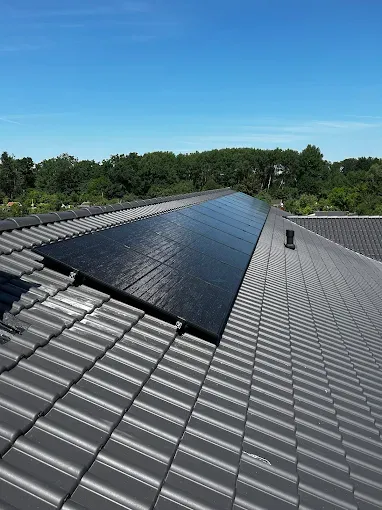 Close-up of a woman with a hand on her chest wearing a black top and white vest, standing outdoors at sunset.