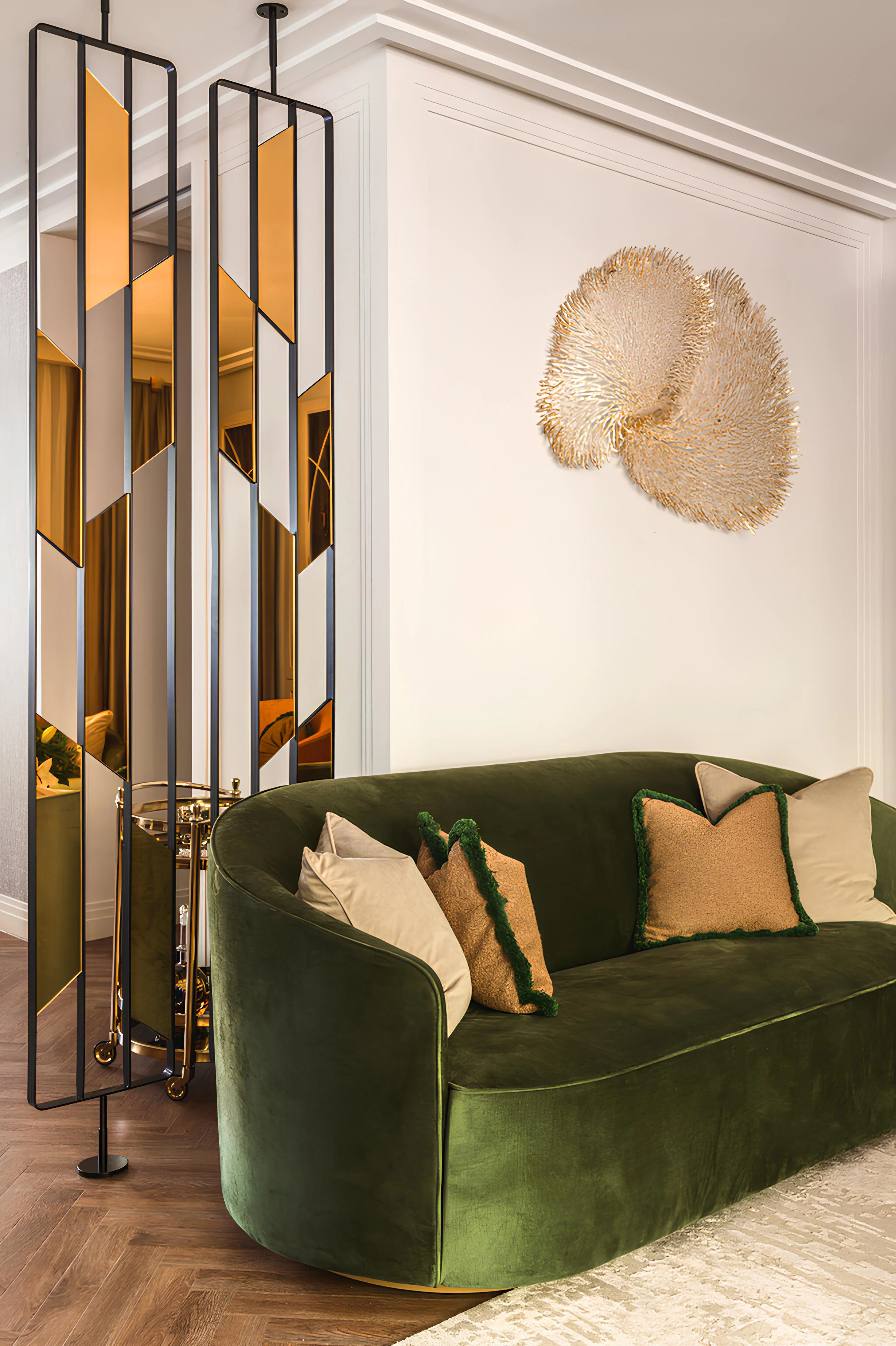 Curved green velvet sofa with beige and green-trimmed pillows in a modern living room.