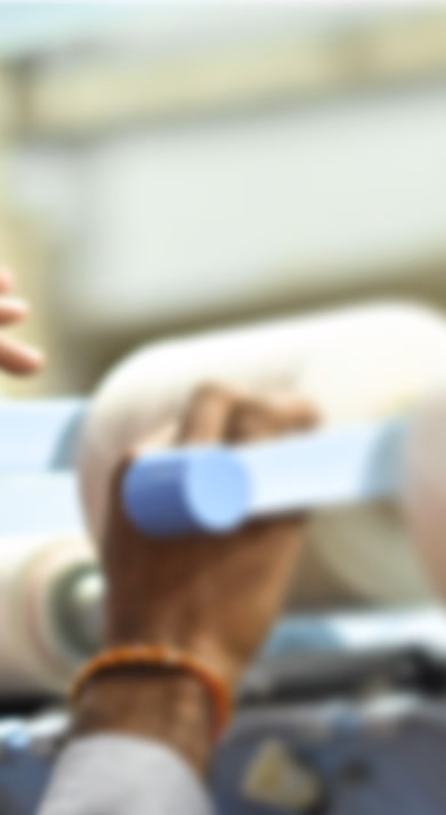 Blurred close-up of a hand holding a piece of light blue material or tape.