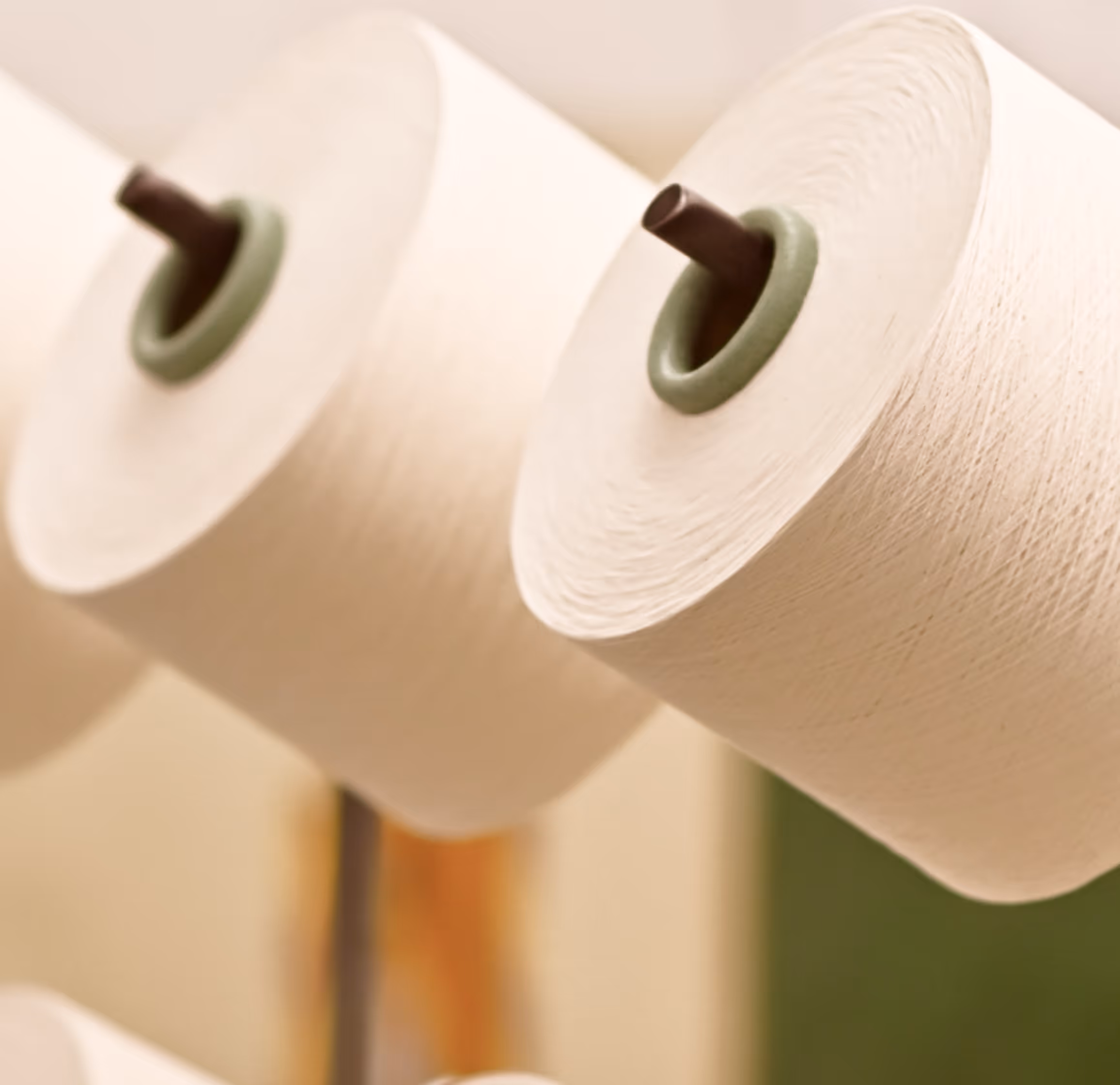 Close-up of large spools of white yarn on a textile machine.