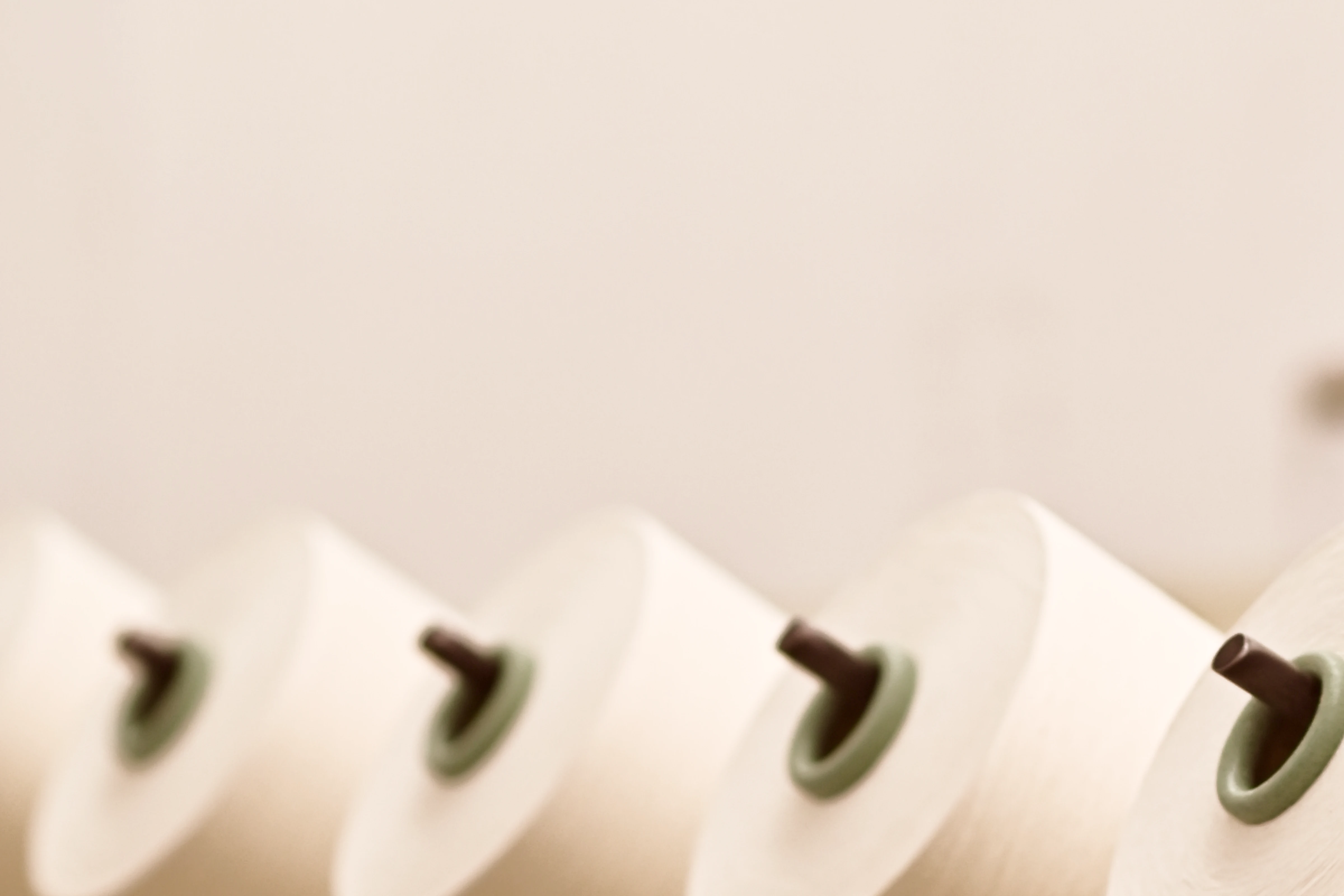 Close-up of several white spools of thread aligned in a row with a shallow depth of field.