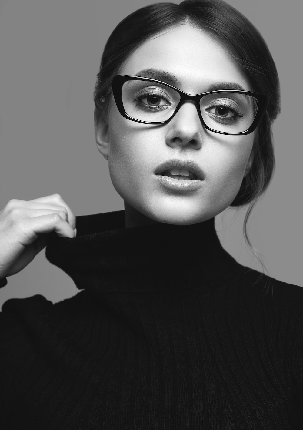 Black and white portrait of a person wearing glasses and black turtleneck