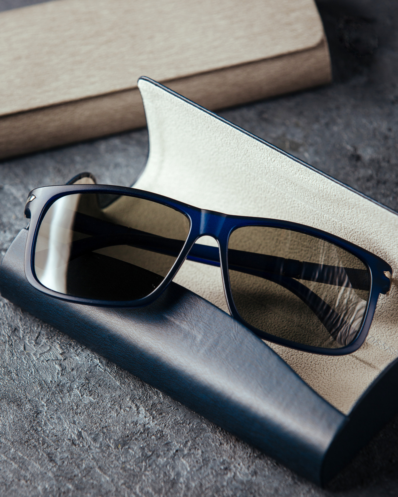 Blue-framed sunglasses resting on an open black and beige textured case.