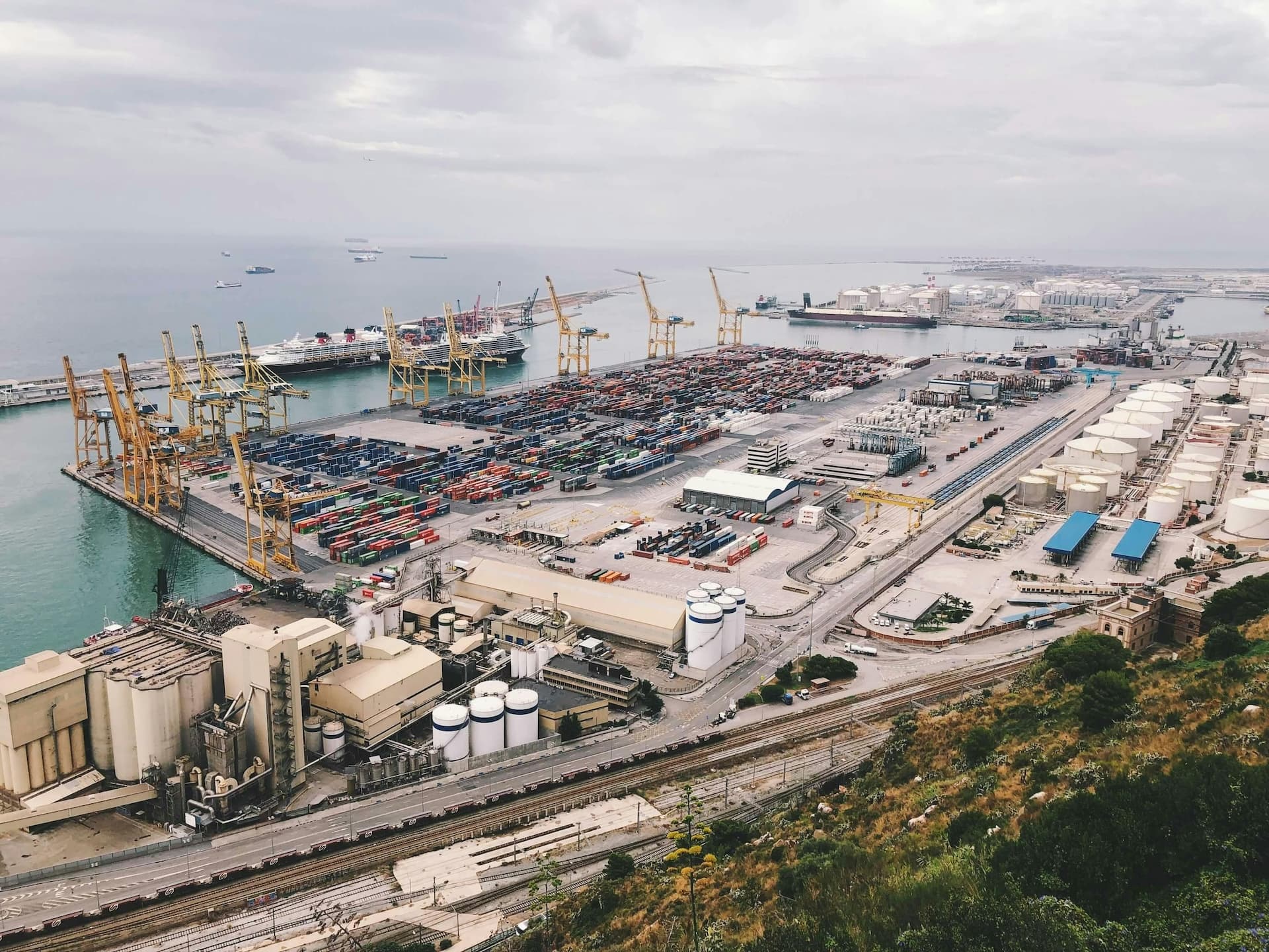 Image of terminal at the port, ocean in the background, few vessels and cranes
