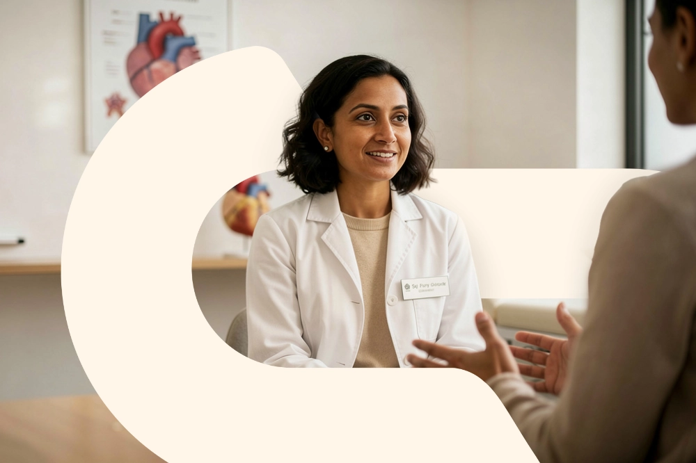 A clinician talking with a patient beside an anatomical heart model